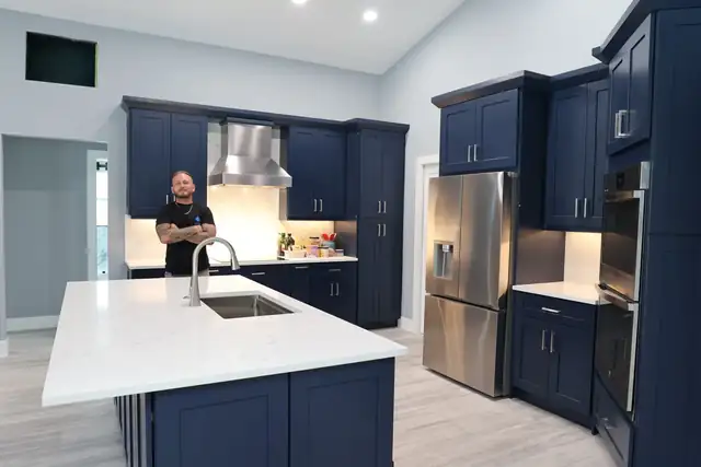 Kitchen with navy shaker cabinets, a white quartz island with an undermount sink and stainless appliances