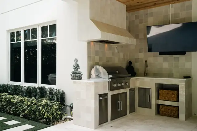 Outdoor kitchen with a built-in stainless grill, stone-look tile, a vent hood and a wood plank ceiling