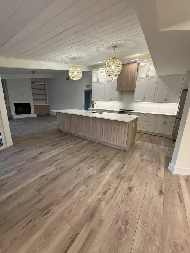 Open-concept kitchen with engineered wood flooring, a long island, shiplap ceiling and woven pendant lights