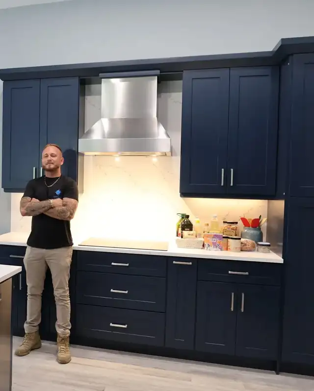 Kitchen remodel with navy shaker cabinets, a stainless range hood and a white tile backsplash