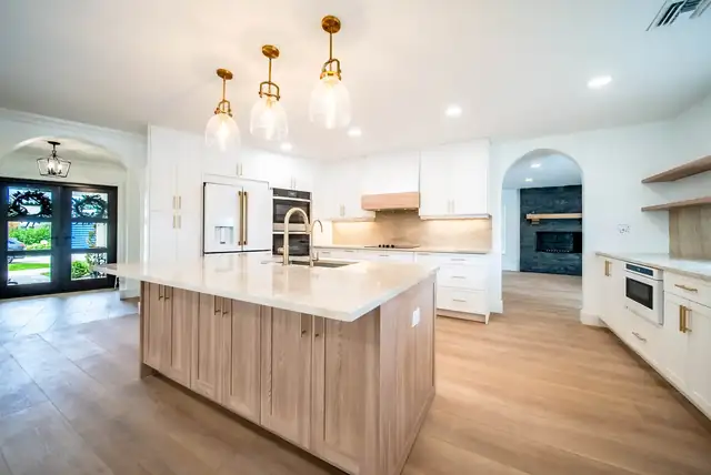 Boca Raton kitchen by North2South with a light oak island, white quartz, white cabinets and glass pendant lights